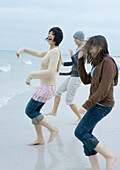 Three young women running toward surf