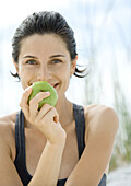 Woman holding up apple, smiling