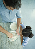 Girl watching as father mixes dough, high angle view