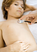 Doctor holding stethoscope to boy's chest