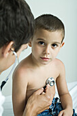 Doctor listening to boy's chest with stethoscope