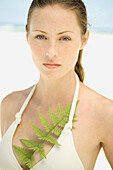 Young woman wearing bathing suit, fern leaf in top