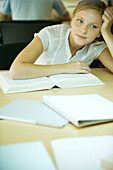 Young woman studying in university library, leaning on book and looking away