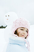 Girl winking at camera, snowman in background