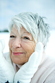 Senior woman holding hands around face, in snowy landscape, portrait