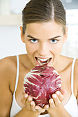 Woman holding up head of radicchio lettuce, ready to take a bite out of it