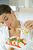 Woman pouring olive oil on antipasto