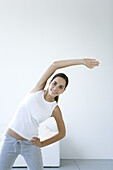 Woman stretching, one arm raised, smiling at camera