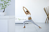 Frau in Yoga-Pose im Wohnzimmer