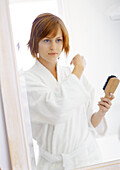 Woman in bathrobe holding hairbrush