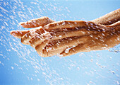 Hands under drops of water, close up