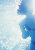 Woman underwater, backlit, low angle view
