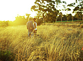 Couple standing in field of tall grass, rear view