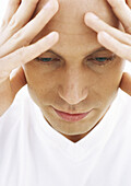 Man holding head, looking down, close-up