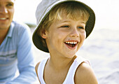 Boy wearing hat on beach with father