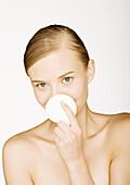 Woman holding up cotton pad in front of mouth