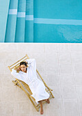 Woman lounging in chair by pool, high angle view