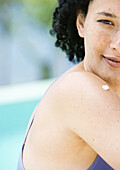 Junge Frau mit einem Tupfer Sonnencreme auf der Schulter