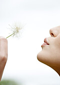 Woman blowing dandelion, close-up