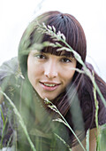Young woman looking through grass