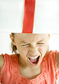 Girl making face, holding present on head