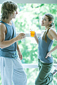 Young adults in exercise clothing, holding drinks and chatting