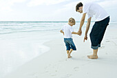 Man and son on beach, man pointing to sand