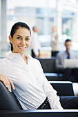 Businesswoman sitting in office lobby, smiling at camera
