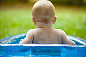 Baby in wading pool, rear view