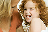 Mother and daughter laughing together, close-up