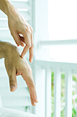 Woman touching man's hands with fingers, cropped view, close-up
