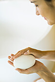 Woman holding bar of soap in hands, looking down, cropped view