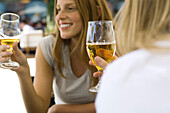 Young women drinking beer at sidewalk cafe, cropped