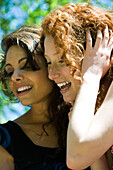 Two young women cheek to cheek, laughing