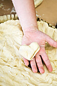 Child's hand holding heart shaped piece of dough