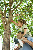 Father helping son retrieve soccer ball stuck in tree