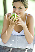 Woman eating apple, looking at camera