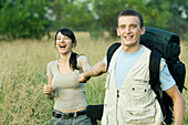 Young couple going for hike, man pulling woman toward him