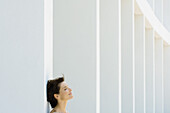Woman leaning against column, eyes closed, cropped view