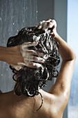 Frau wäscht ihr Haar unter der Dusche