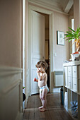 Toddler boy standing in hall, eating a snack