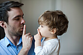 Father teaching toddler son to hush