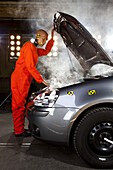A crash test dummy checking under the hood of a smoking car
