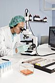 A lab technician looking into a microscope in a laboratory