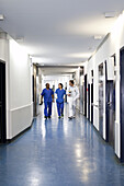 Three medical professionals walking together down a corridor in a hospital