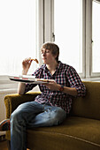 A teenage boy eating delivery pizza