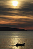 A silhouetted person in a motorboat near Cres on the Adriatic Sea, Croatia