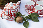 A ceramic tea set and a pear on a table