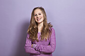 A smiling teenage girl with arms crossed, portrait, studio shot