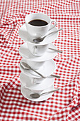 Stack of coffee cups and saucers with coffee in them